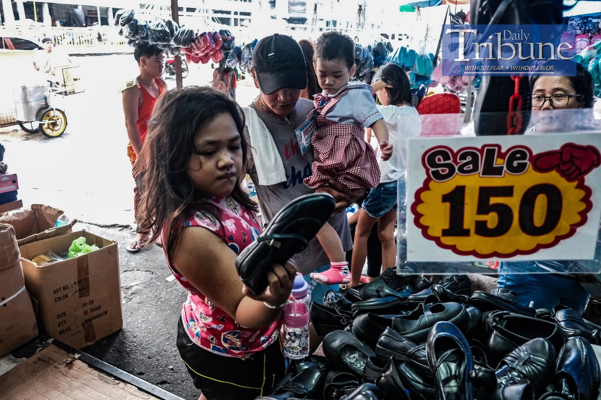 Edwin Ibanez, 55 years old, takes her daughter Precious, 4 years old, to buy new shoes with the help of her older sister Princess Nicole, 7 years old on July 18, 2024. PHOTO BY YUMMIE DINGDING